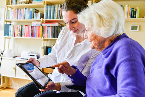 Zorgverlener kijkt toe terwijl cliënt iets aanwijst op een tablet